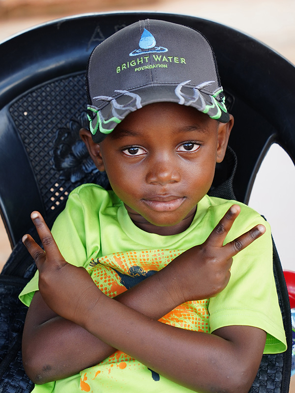 Boy in Bright Water shirt giving peace sign.